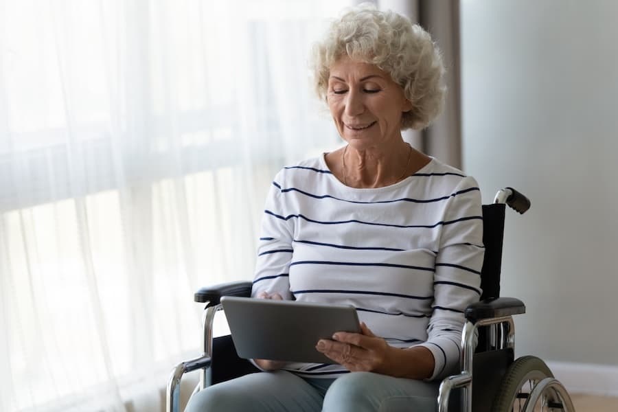 Elderly woman in a wheelchair, exploring a tablet with curiosity